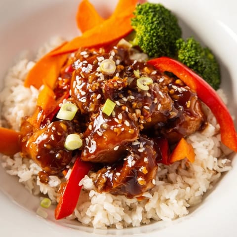 Nahaufnahme von perfekt gebratenem Teriyaki-Hühnchen, glänzend mit süßer Soße, über dampfendem Reis.