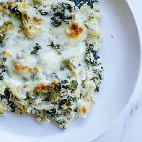 A rich, close-up shot of a bubbling spinach artichoke dip, perfect for sharing.