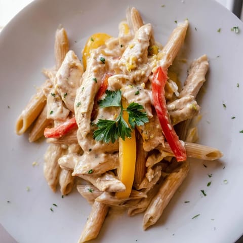 Cremige Cajun Chicken Pasta Lite mit al dente Penne, saftigen Hühnerstreifen und bunten Paprikascheiben, verfeinert mit würziger Cajun-Soße, Parmesan und frischer Petersilie garniert – perfekt für ein leichtes, aromatisches Abendessen.