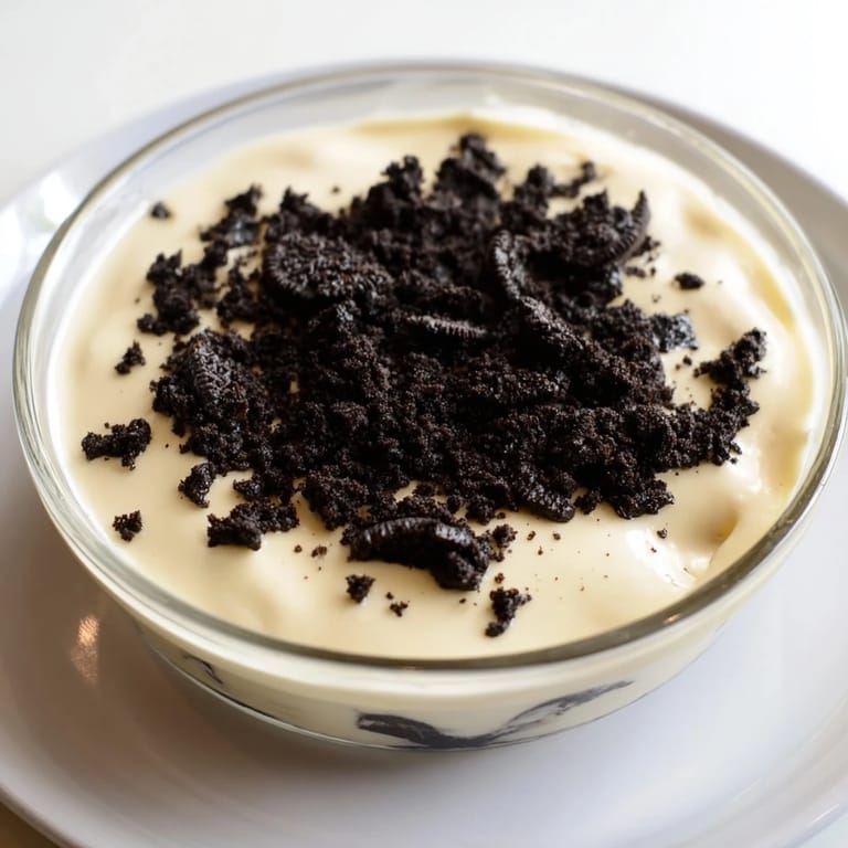 A close-up of a vanilla pudding with crushed Oreos, ready to be enjoyed as a cool dessert.