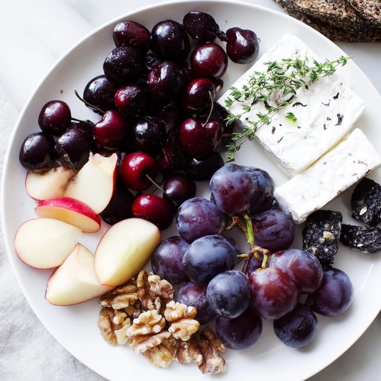 The Midnight Orchard cheese board showcases dark cherries, plums, grapes, and creamy goat cheese arranged artfully.