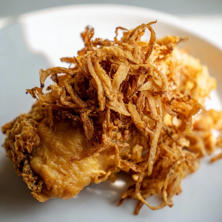 Close-up of a Crispy Onion Chicken Sandwich, highlighting juicy buttermilk chicken and creamy aioli on a soft bun.